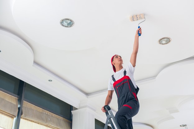 Young painter painting the ceiling in construction concept