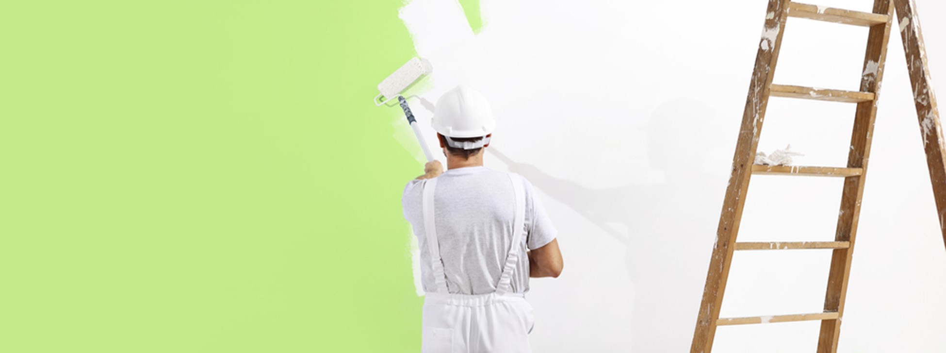 painter man at work with a paint roller, wall painting green color ecological concept.